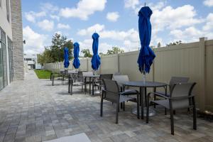 坦帕Holiday Inn Express & Suites Tampa Stadium - Airport Area, an IHG Hotel的一排带蓝色遮阳伞的桌椅