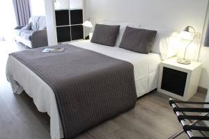 巴塞罗那卡拉布里亚雅典娜公寓式酒店的卧室配有一张白色大床和一把椅子