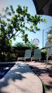 锡瓦塔塔内霍Hotel Villas Ema的两个长椅,坐在一个带时钟的游泳池旁边