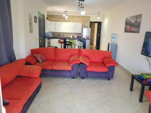 艾因苏赫纳Telal Ground Floor 2 bedroms的一间带红色沙发的客厅和一间厨房
