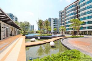 Ban Khlong Samrongsupalai city resort的一座有楼房的城市中,有一座庭院,里面设有池塘