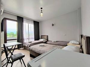 科布列季Elgabi Hotel Kobuleti的客房设有两张床、一张桌子和一扇窗户。