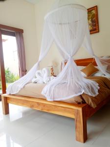 德格拉朗Ubud nadi villa的卧室配有带白色窗帘的天蓬床