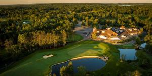 巴克斯特AmericInn by Wyndham Baxter Brainerd的享有带高尔夫球场的大房子的空中景色