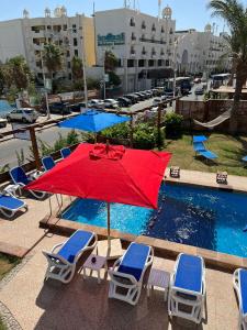 赫尔格达Serafy City Center Hostel and Pool for Foreigners Adults Only的游泳池旁的红色遮阳伞和椅子