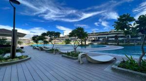 马尼拉1BR Prisma Residences DMCI Stylish Condo的一个带长椅和树木的游泳池的度假酒店
