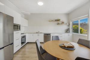 黄金海岸Skyline Apartments Unit 5的白色的厨房配有木桌和椅子