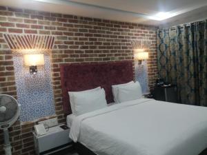 卡拉尔哥特Hotel Hayatt Sukkur的一间卧室设有一张床和砖墙