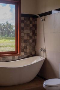 乌布New Private Pool Villa - Villa Dhea Ubud的带浴缸、卫生间和窗户的浴室