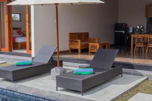 乌布New Private Pool Villa - Villa Dhea Ubud的游泳池旁的两把椅子和一把遮阳伞