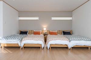 白滨PEACE OF REST SHIRAHAMA的客房内设有两张床,铺有木地板,设有窗户。