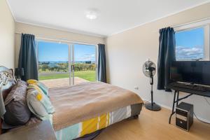 凯塔亚Tokerau Magic - Karikari Peninsula Holiday Home的一间卧室设有一张床和一个大窗户