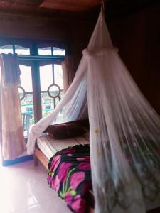 克里穆图WATUGANA BUNGALOW KELIMUTU的窗户客房内的一张带天蓬的床