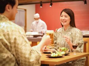 音更町笹井酒店的坐在桌子旁喝杯啤酒的男人和女人