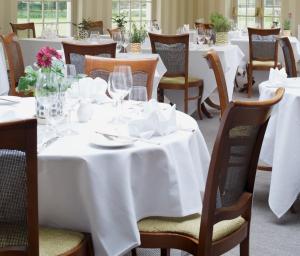 格里姆斯顿Congham Hall Hotel & Spa的一间设有白色桌椅的用餐室