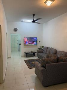马六甲Anak Air Homestay, Serkam Islam Guest Only的客厅配有2张沙发和1台平面电视