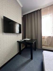 阿克托比Бутик-отель Мажор的一间设有一张桌子的房间,墙上配有电视