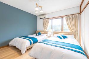 白滨Azami Ann Maisonette的卧室设有两张床,拥有蓝色的墙壁和窗户。