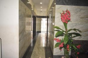 印多尔Hotel Lakshya Sheesh Mahal Indore的花瓶里种着红花的花的走廊