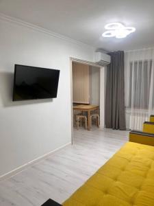 阿拉木图2-х комнатная в центре район ЦУМа的一间带电视和黄色沙发的客厅