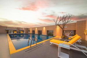 海得拉巴Marigold Hotel的一个带黄色沙发和桌子的游泳池