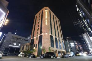 蔚山Brown Dot Hotel Ulsan Samsan的一座高大的砖砌建筑,停车场有汽车停放