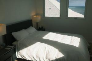 檀香山Aloha Beachfront ホノルル - Hawaii Kai的卧室配有一张白色大床和两个窗户