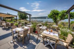 赖兴瑙Strandhotel Löchnerhaus的一间带桌椅并享有水景的餐厅