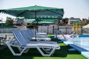 卡罗利诺-布加兹Weekend Family Hotel的游泳池旁的一排躺椅和遮阳伞