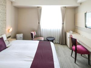 守山Vessel Inn Shigamoriyamaekimae的酒店客房,配有一张床、一张桌子和椅子