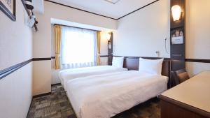 大阪Toyoko Inn Osaka Tsuruhashi Ekimae的酒店客房设有两张床和窗户。
