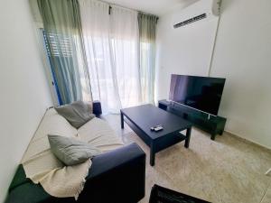 皮拉Beach Vibes Apartment的带沙发、电视和桌子的客厅