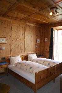 Vicosoprano阿尔伯格皮兹坎酒店的一间带两张床铺的卧室,位于带木墙的房间内