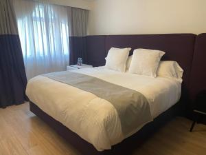 墨西哥城Casa Amari的卧室配有一张带白色床单和枕头的大床。