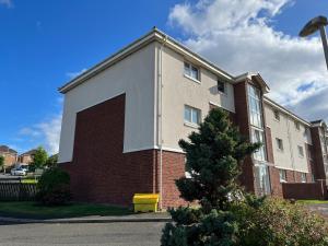 东基尔布赖德Flat Three, 212 Eaglesham Road, East Kilbride, Glasgow的砖砌的建筑,旁边有一扇大门