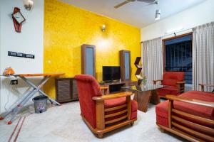 班加罗尔SS Mystic Apartotel的客厅设有黄色墙壁和红色椅子