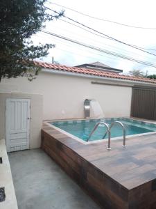 瓜鲁雅Casa espaçosa com Piscina e Churrasqueira 2 dorm的一个带木甲板和浴缸的游泳池