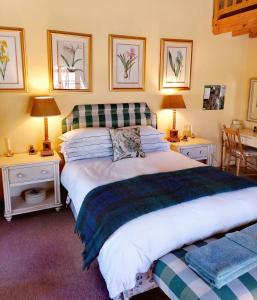 克拉伦斯Peebles Cottage的一间卧室配有一张大床、两张桌子和两盏灯。