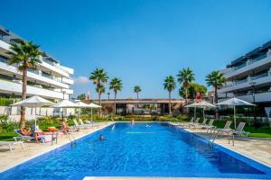 弗拉门卡海滩Flamenca Village Resort apt 172的一座带椅子和棕榈树的游泳池以及一座建筑