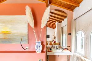 Baurech1986MALAGAR的浴室设有橙色墙壁、水槽和带羽毛的花瓶。