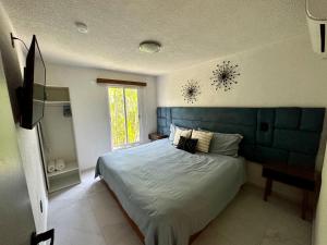 伊斯塔帕CORMORAN COZY CONDO IN IXTAPA的一间卧室配有一张带蓝色床头板的床和窗户
