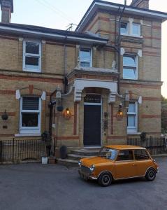 赖德The Victorian lodge的停在房子前面的一辆小型橙色汽车