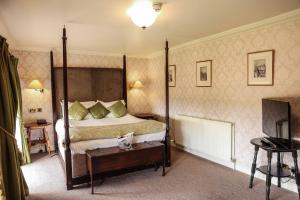塔德卡斯特Hazlewood Castle & Spa的一间卧室配有四柱床和电视。
