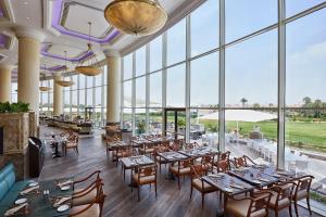 开罗开罗JW万豪酒店的餐厅设有桌椅和大窗户。