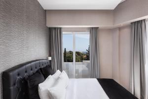 雅典Kreoli Suites Glyfada的一间卧室设有一张床和一个大窗户