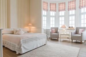格吕克斯堡格吕克斯堡斯滕德酒店的一间白色卧室,配有一张床和两把椅子