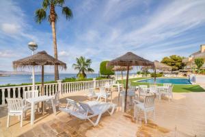 卡塔赫纳Dúplex Villas Romanas con vistas espectaculares的一个带白色椅子和遮阳伞的庭院和一个游泳池