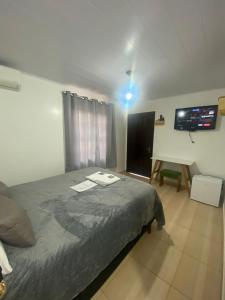 波梅罗迪Suites da Rota - Pomerode SC的一间卧室配有一张床和一台平面电视
