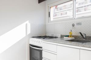 布宜诺斯艾利斯Lumimoso departamento en Buenos Aires 1 dorm的白色的厨房配有炉灶和水槽