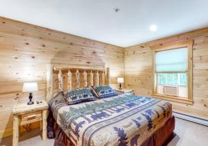 CarrabassettKingslanding Cabin的一间卧室设有一张床和木墙